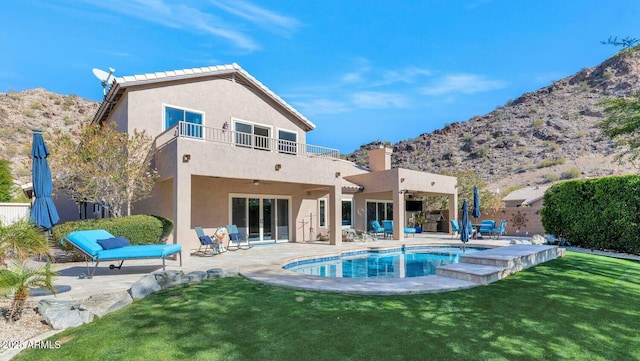 back of house with a balcony, a fenced in pool, a yard, and a patio