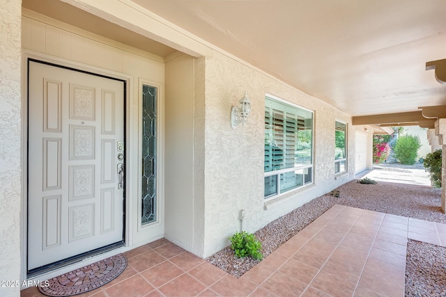 doorway to property featuring a porch and stucco siding