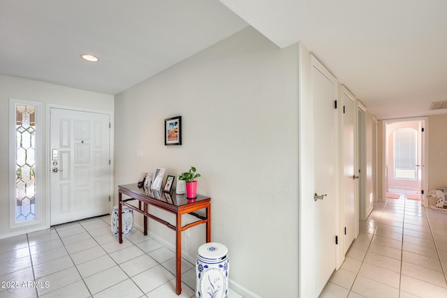 entrance foyer with visible vents, baseboards, light tile patterned flooring, and arched walkways
