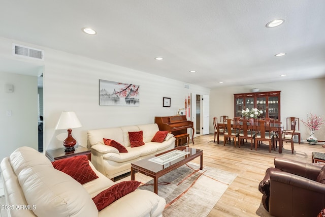 living room with light wood-style floors, visible vents, and recessed lighting