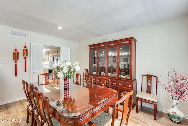 dining room featuring light wood finished floors, visible vents, baseboards, and recessed lighting