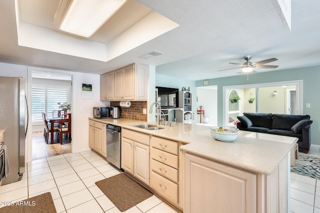 kitchen with a sink, a peninsula, light tile patterned flooring, and appliances with stainless steel finishes