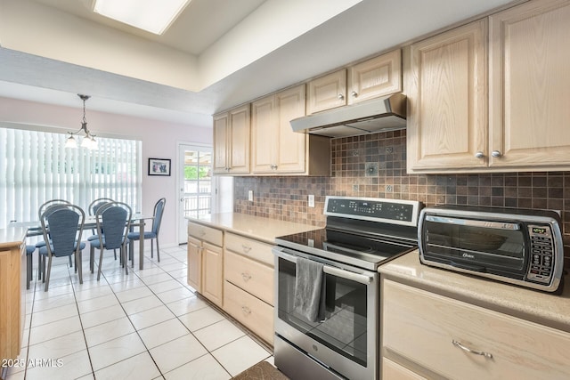 kitchen with a toaster, under cabinet range hood, light tile patterned floors, tasteful backsplash, and electric range