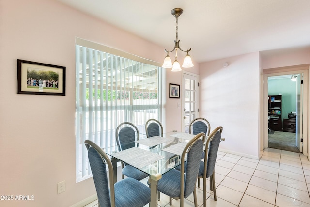 dining area featuring an inviting chandelier, light tile patterned flooring, and baseboards