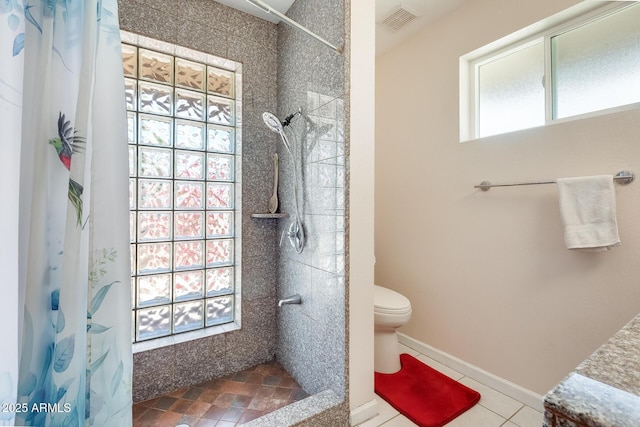 bathroom featuring toilet, visible vents, baseboards, and tiled shower