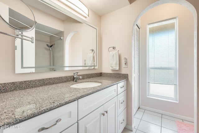 bathroom with baseboards, walk in shower, tile patterned floors, and vanity