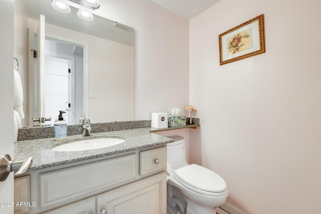 half bath with toilet, visible vents, and vanity