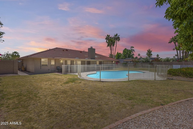 pool at dusk featuring fence, a fenced in pool, a patio area, and a lawn