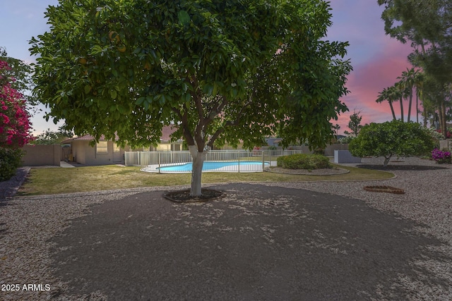 yard at dusk with fence and a fenced in pool