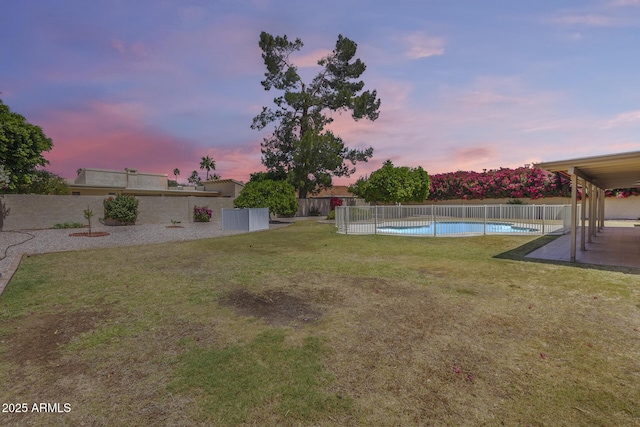 yard at dusk featuring a fenced backyard, a patio area, and a fenced in pool