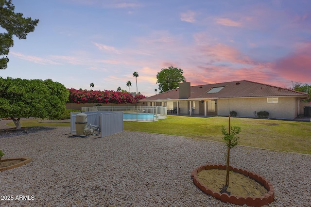yard at dusk featuring fence, a patio, and a fenced in pool