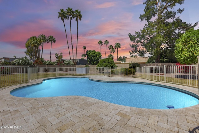 pool at dusk featuring a patio, fence, and a fenced in pool
