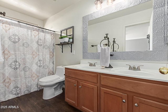 full bathroom featuring wood finished floors, double vanity, and toilet