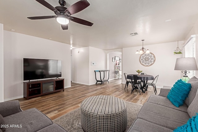 living room with wood finished floors, arched walkways, a chandelier, and baseboards