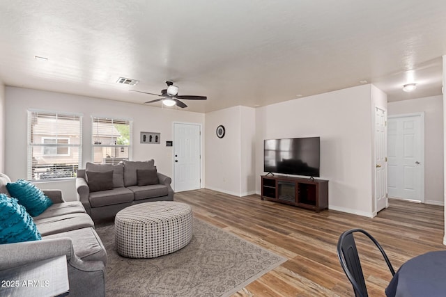living area featuring wood finished floors, ceiling fan, and baseboards