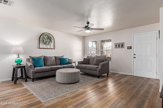 living area with a ceiling fan, wood finished floors, and baseboards