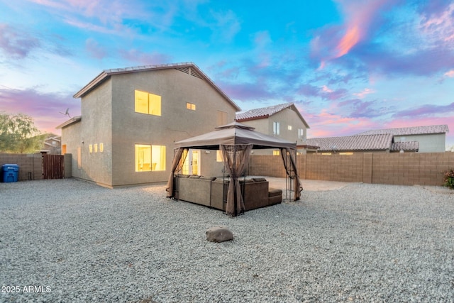 back house at dusk with a gazebo and a patio area