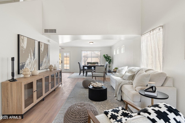 living room featuring french doors, wood-type flooring, and a high ceiling