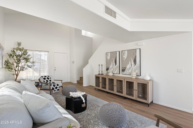 living room with hardwood / wood-style floors and a towering ceiling