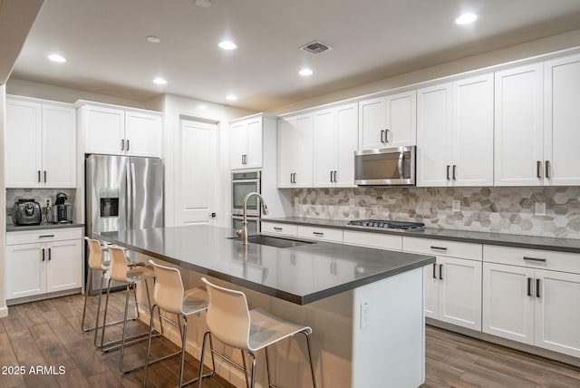 923 W Yellowstone Way, Chandler, AZ 85248 - kitchen featuring stainless steel appliances, dark countertops, backsplash, dark wood-style flooring, and a kitchen bar