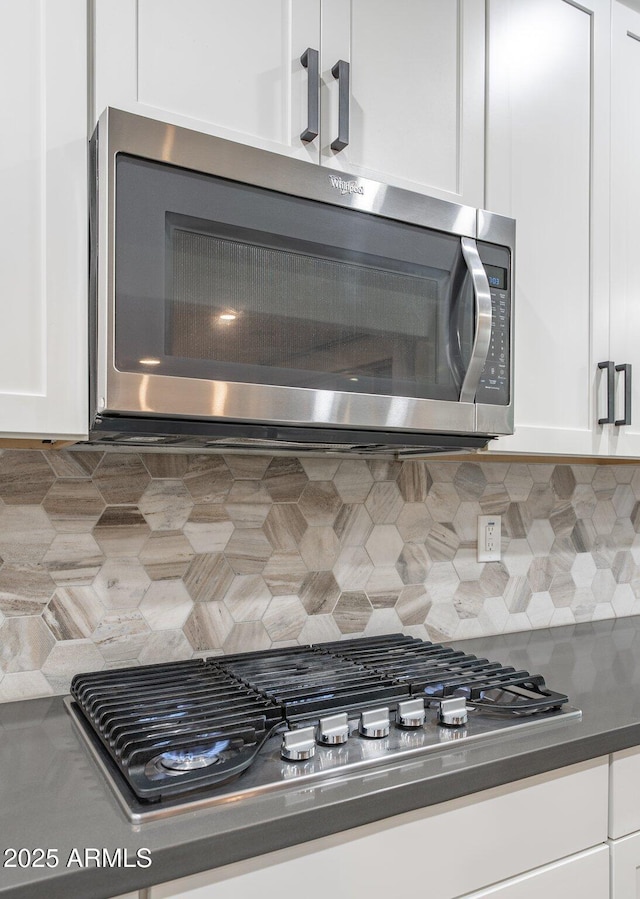 923 W Yellowstone Way, Chandler, AZ 85248 - kitchen view of stainless steel appliances, white cabinetry, tasteful backsplash, and dark countertops