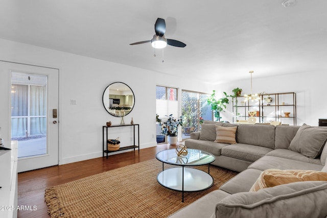 living room with ceiling fan with notable chandelier and dark wood-type flooring