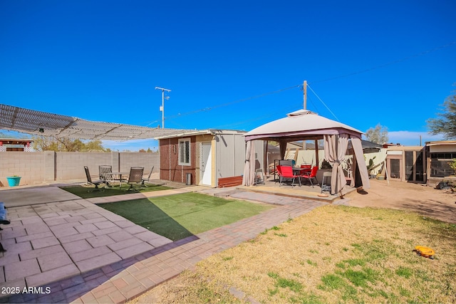 rear view of house with a fenced backyard, a storage shed, an outdoor structure, a gazebo, and a patio area