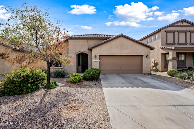 view of front of home with a garage, concrete driveway, a tile roof, and stucco siding