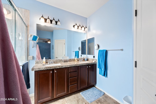 bathroom with double vanity, a shower stall, a ceiling fan, and a sink