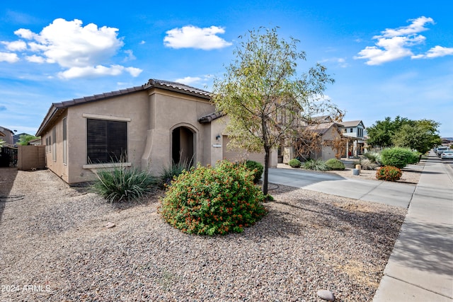 view of front of home featuring driveway, fence, a tile roof, and stucco siding