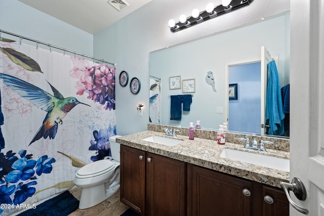 bathroom featuring double vanity, visible vents, toilet, and a sink