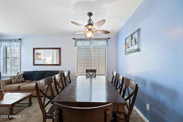 carpeted dining space featuring baseboards and a ceiling fan