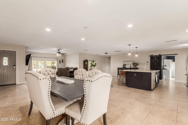 dining space featuring ceiling fan, a barn door, and sink