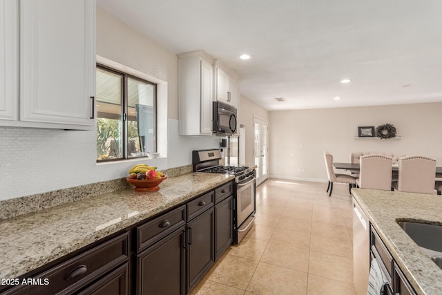 kitchen with white cabinetry, light stone counters, dark brown cabinetry, and stainless steel gas range oven