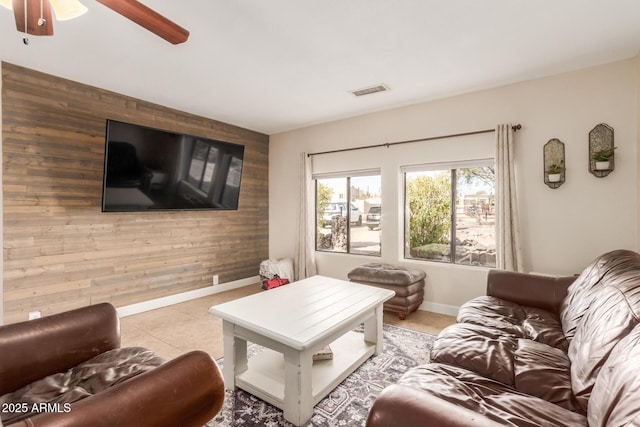 living room with ceiling fan, light tile patterned floors, and wood walls