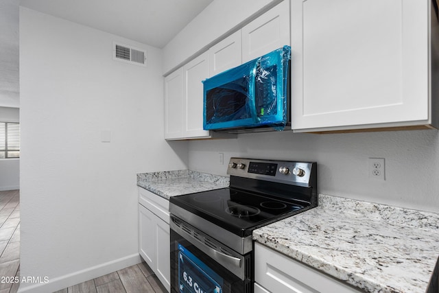 kitchen with white cabinets, visible vents, light wood finished floors, and stainless steel electric stove