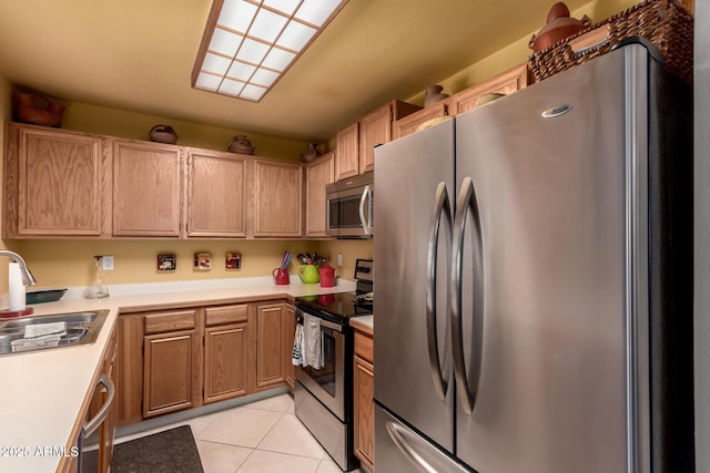 kitchen featuring appliances with stainless steel finishes, light countertops, a sink, and light tile patterned floors