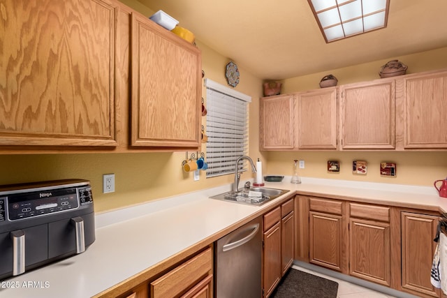 kitchen featuring light tile patterned floors, a sink, light countertops, stainless steel dishwasher, and light brown cabinetry