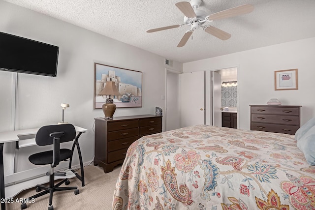 bedroom with visible vents, light colored carpet, ensuite bath, ceiling fan, and a textured ceiling