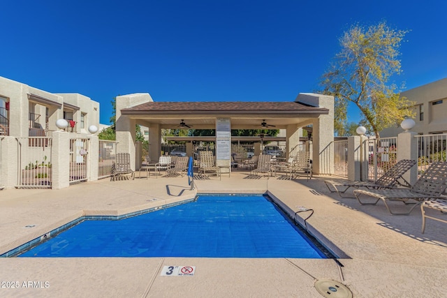 community pool with fence, a ceiling fan, and a patio