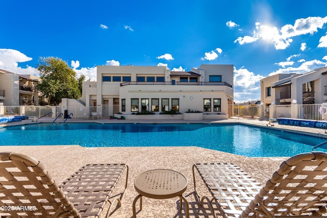 community pool with a patio and fence