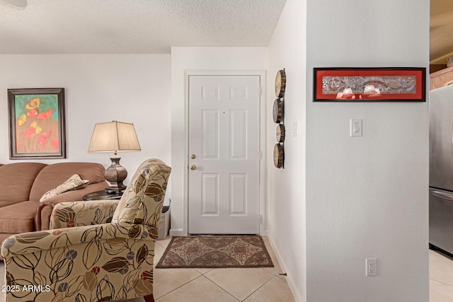 tiled foyer entrance featuring a textured ceiling and baseboards