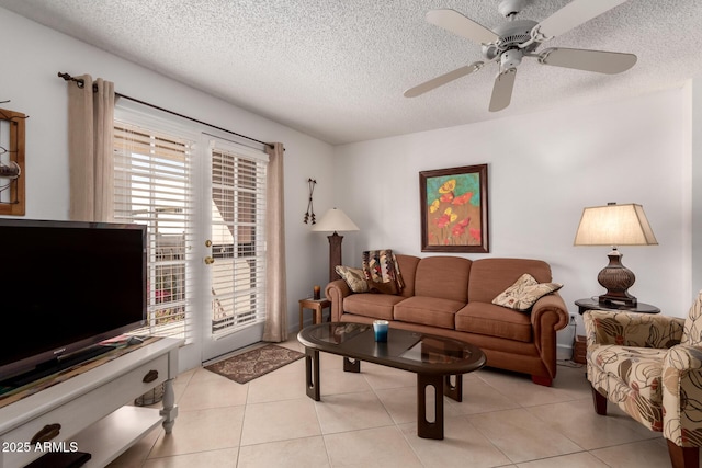 living room featuring light tile patterned floors, a ceiling fan, and a textured ceiling