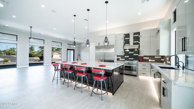 kitchen with pendant lighting, sink, tasteful backsplash, stainless steel appliances, and a spacious island