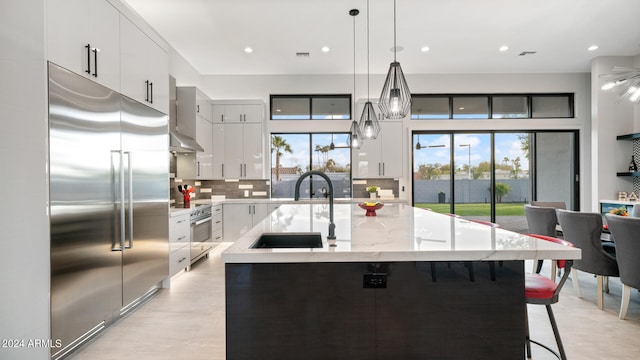 kitchen with pendant lighting, sink, a kitchen island with sink, white cabinetry, and stainless steel appliances