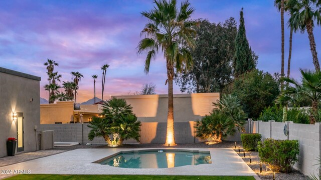 pool at dusk featuring a patio