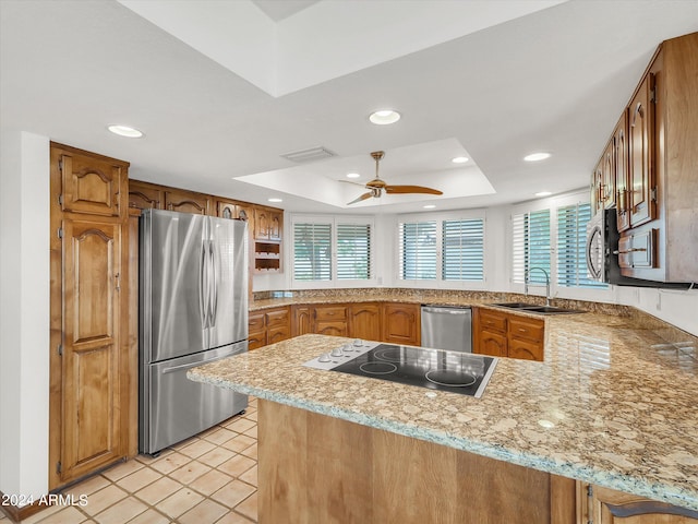 kitchen with ceiling fan, stainless steel appliances, sink, kitchen peninsula, and a tray ceiling