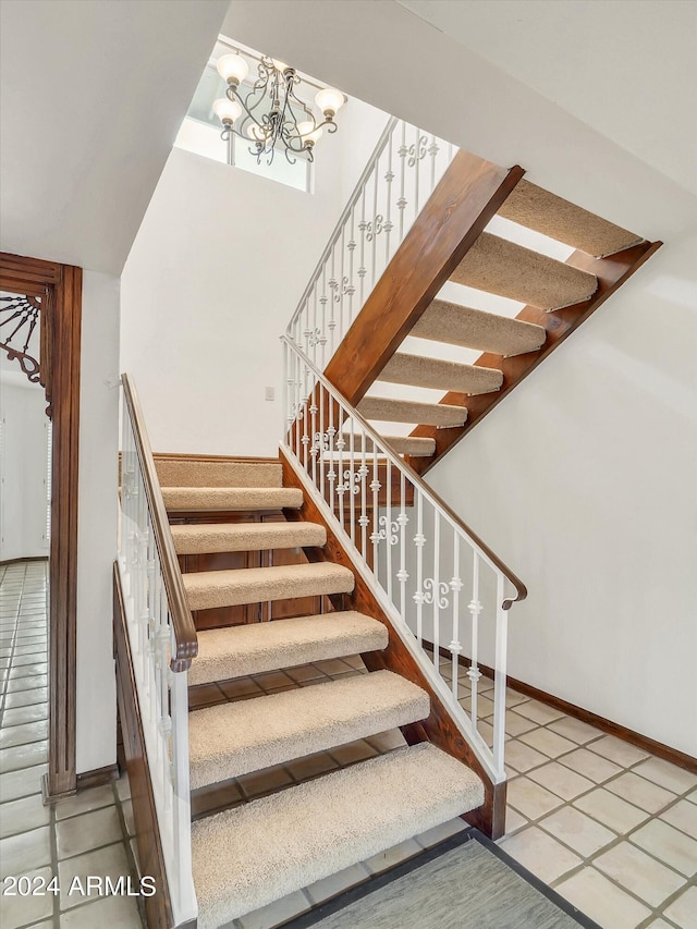 stairs with an inviting chandelier, light tile flooring, and a high ceiling