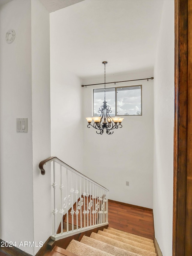 stairs with a notable chandelier and hardwood / wood-style floors