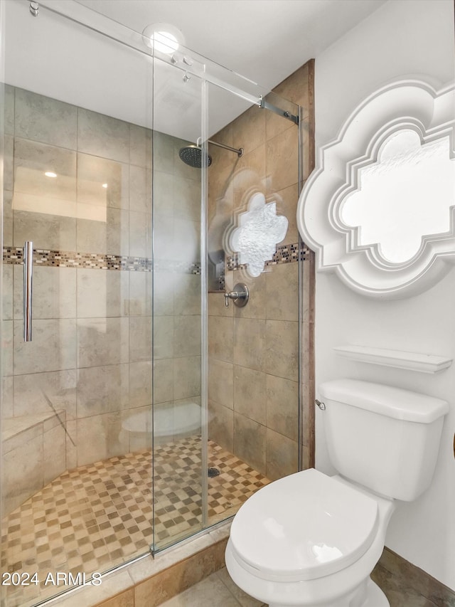 bathroom featuring a shower with door, tile floors, and toilet